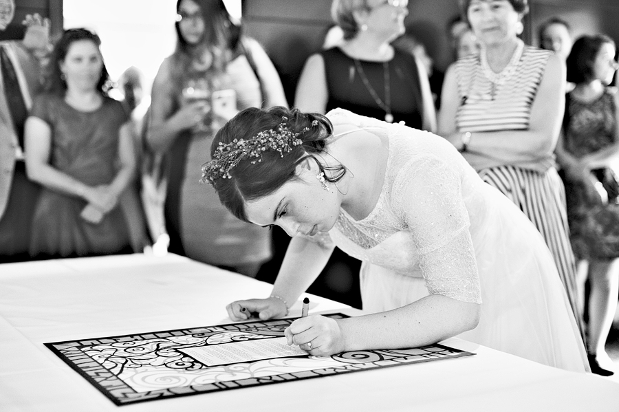 bride signing the ketubah at a cambridge, massachusetts wedding